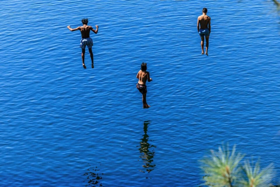 Tyler State Park with kids — three boys leaping into a sunlit lake on a summer day